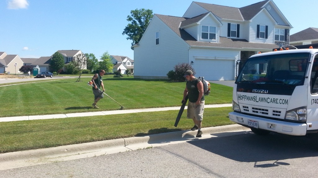 Hoffmans Lawn & Fertilization crew trimming and blowing a residential property in Delaware, OH