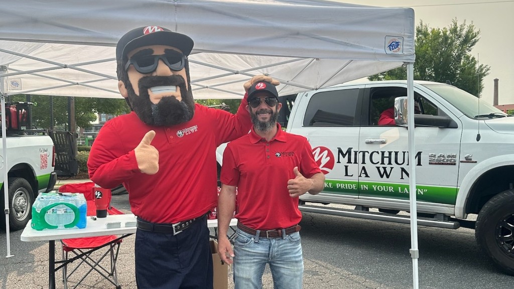 Marcus Mitchum with the Mitchum Lawn mascot at a community event in Columbus, GA