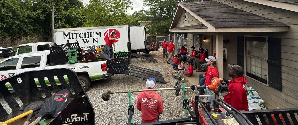 Mitchum Lawn team members gathered at a job site with trucks and equipment in Columbus, GA