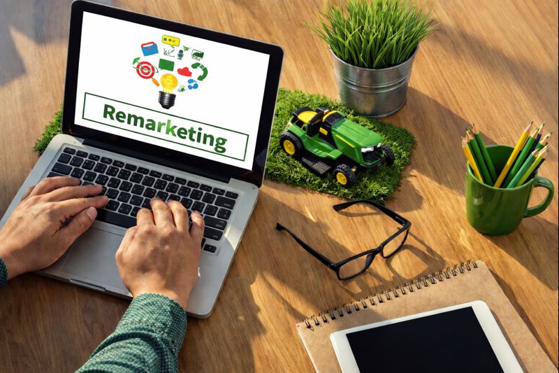 Remarketing concept with laptop, lawn care tools, and digital marketing icons showing re-engagement campaigns